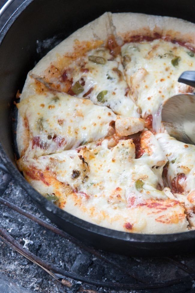 the pizza is being cooked on the stove with a spatula in it's hand