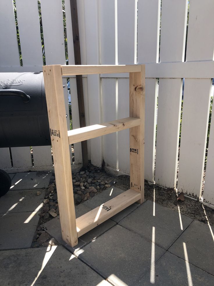 a wooden shelf sitting next to a white fence