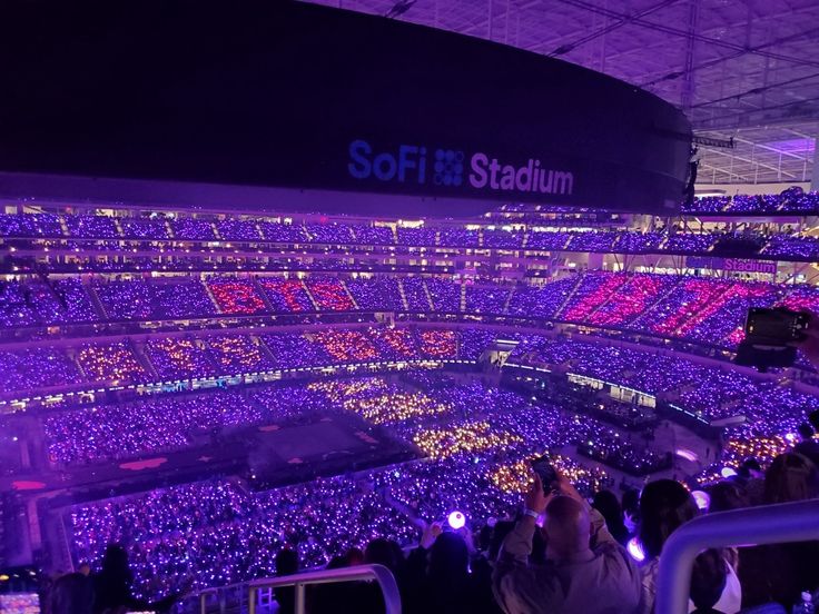 a stadium filled with lots of people and purple lights on the side of the seats