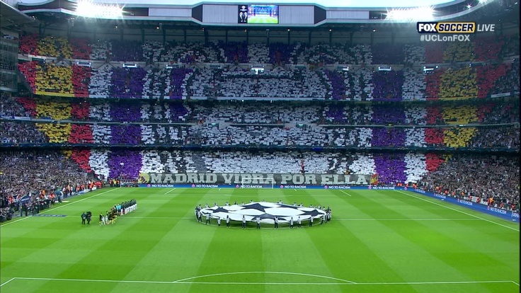 a soccer stadium filled with lots of fans and players around a large round flag on the field