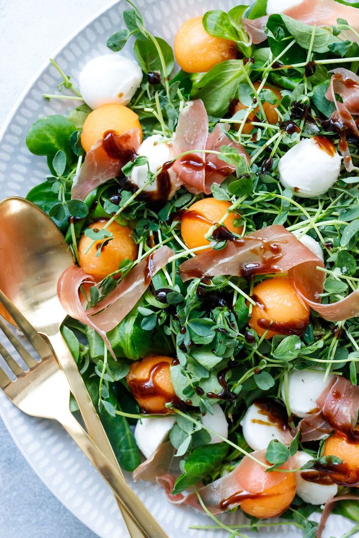 a salad with oranges, mozzarella and spinach on a white plate