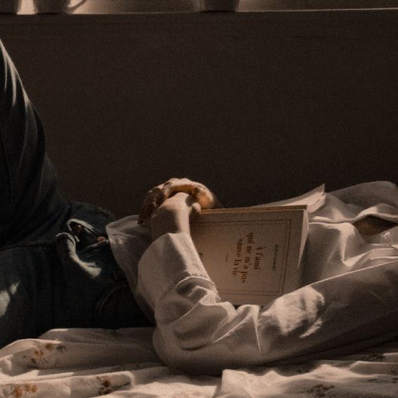 a person laying in bed reading a book