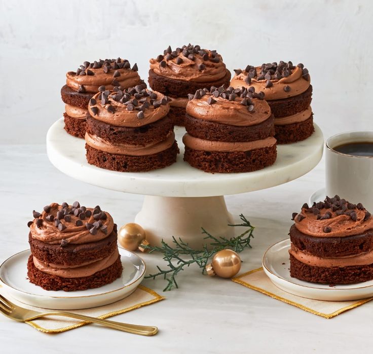 chocolate cake with frosting and sprinkles on a white platter next to two cups of coffee