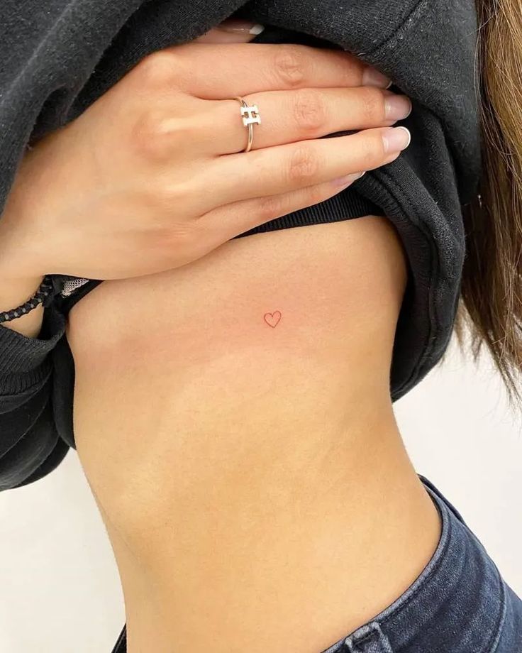 a woman with a small heart tattoo on her stomach