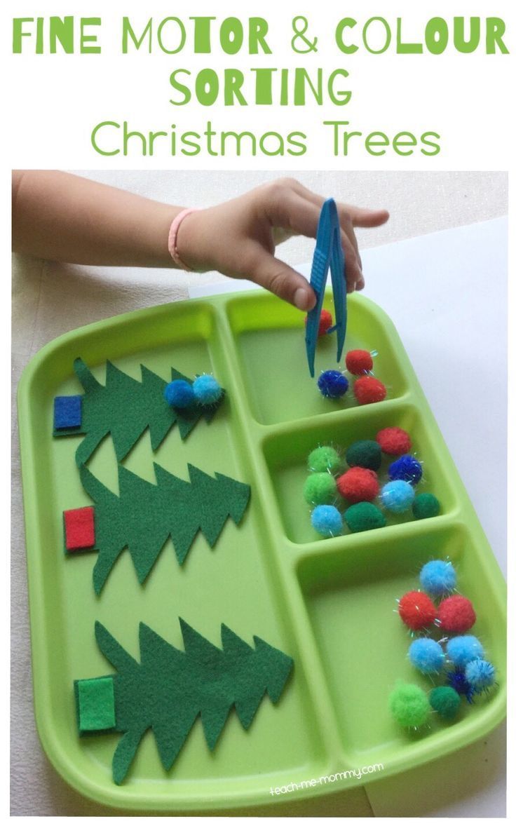 a green tray filled with christmas trees and pom poms