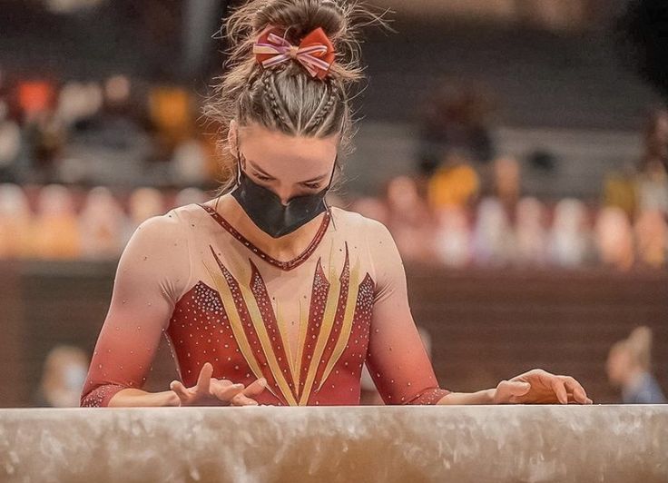 a woman in a red and yellow leotard with a black mask on her face