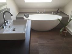 a white bath tub sitting under a window next to a sink in a bathroom below a skylight