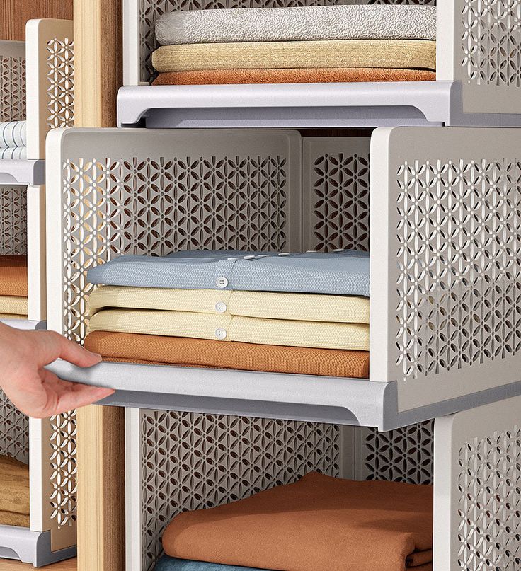 a person is reaching for some folded cloths on a shelving unit in a closet