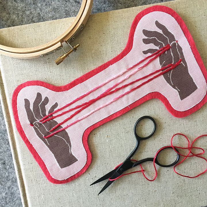 a pair of scissors sitting on top of a piece of fabric next to some knitting needles