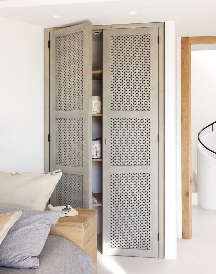 an open closet in the corner of a bedroom next to a bed with pillows on it