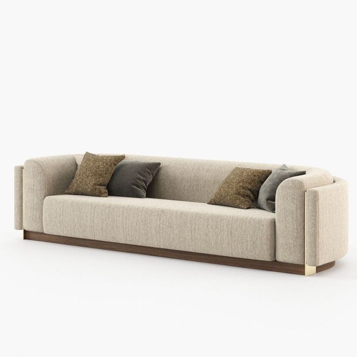 a white couch with pillows on it in front of a gray wall and light brown floor