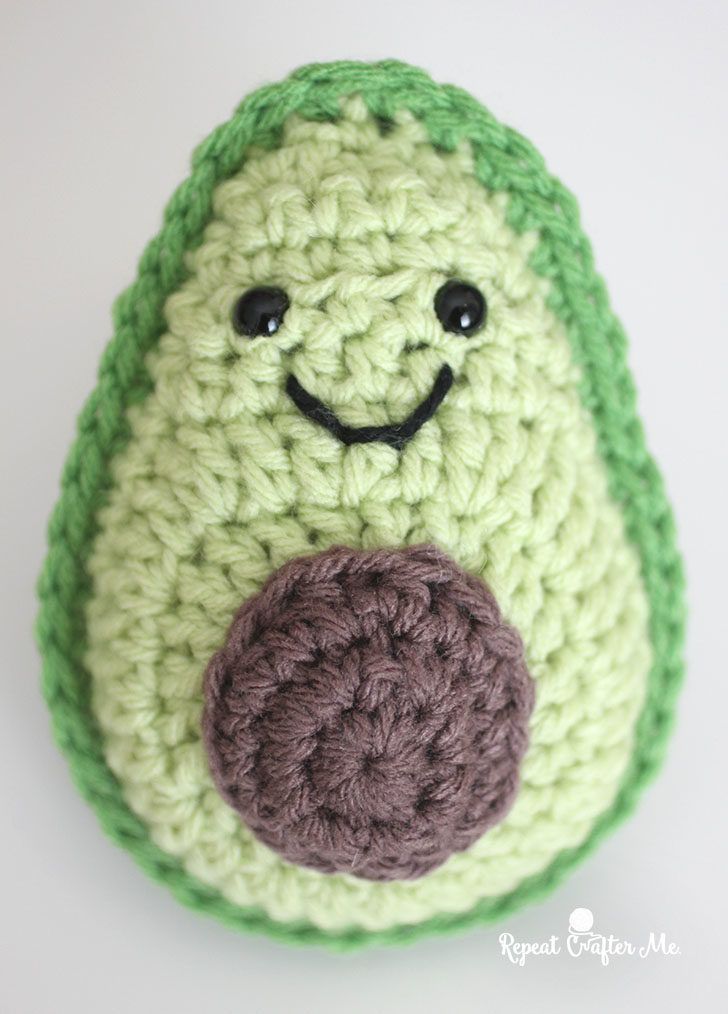 a crocheted green and white object with a smile on it's face