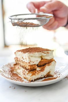 a person grating cinnamon on top of a dessert with ice cream and graham crackers