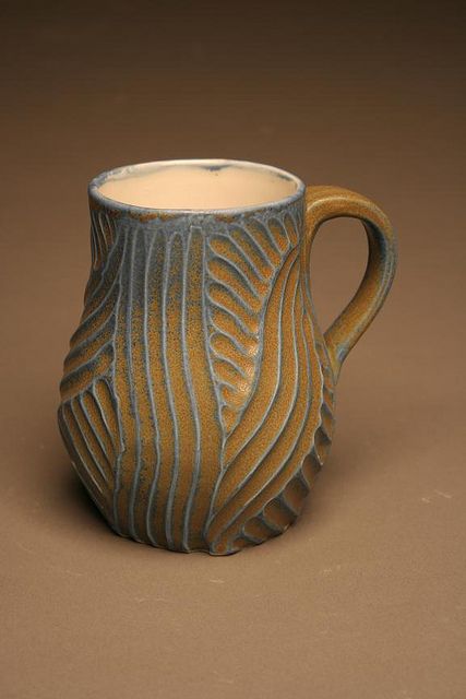 a ceramic mug with wavy lines on the outside and inside, sitting on a brown surface