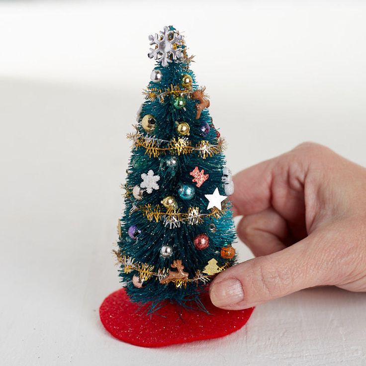 a miniature christmas tree is being held by a hand