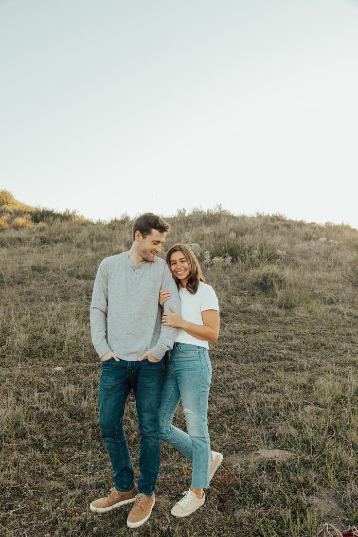 a man and woman are standing in the middle of a field with their arms around each other