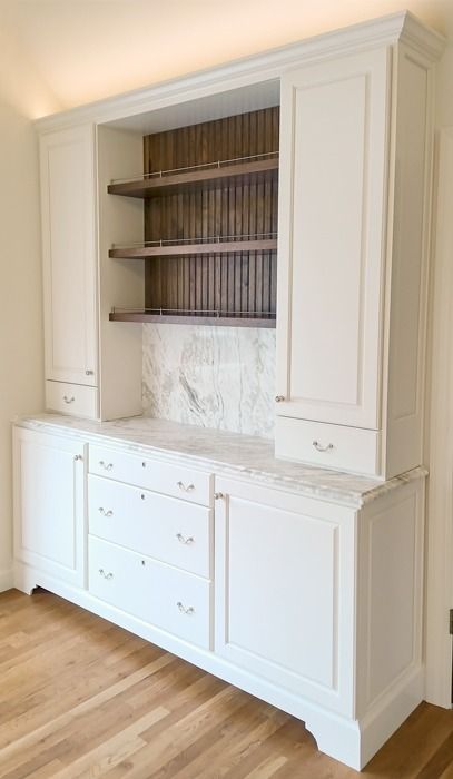 an empty room with white cabinets and wood floors