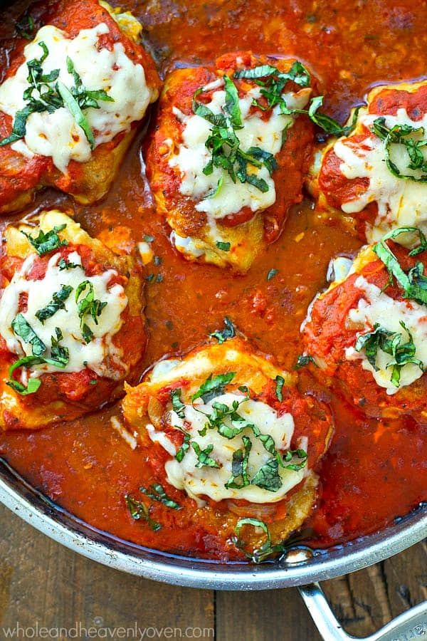 several stuffed shells covered in sauce and parmesan cheese, on a wooden table