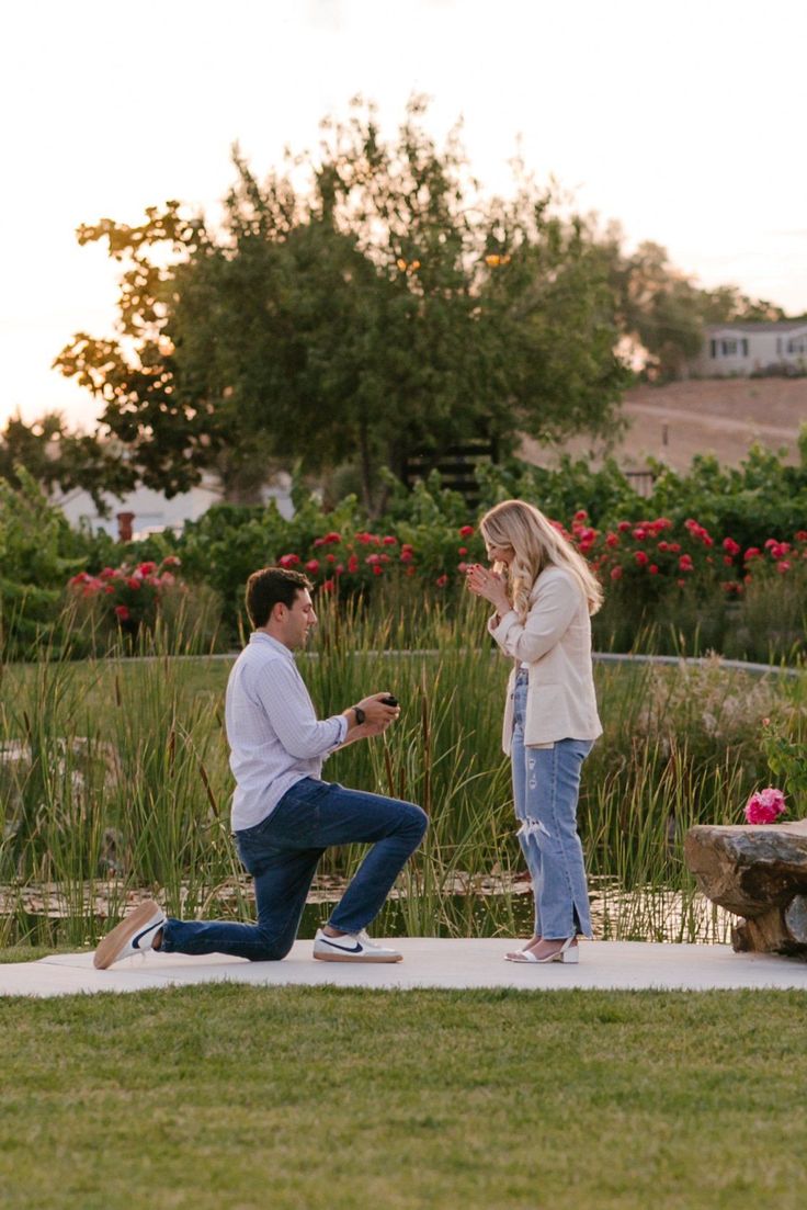 a man kneeling down next to a woman who is holding a cell phone in her hand