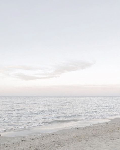 two people walking on the beach with surfboards