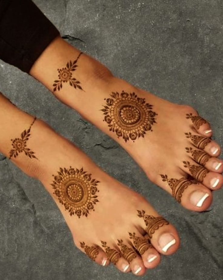 two feet with henna tattoos on them, one has an intricate design and the other has