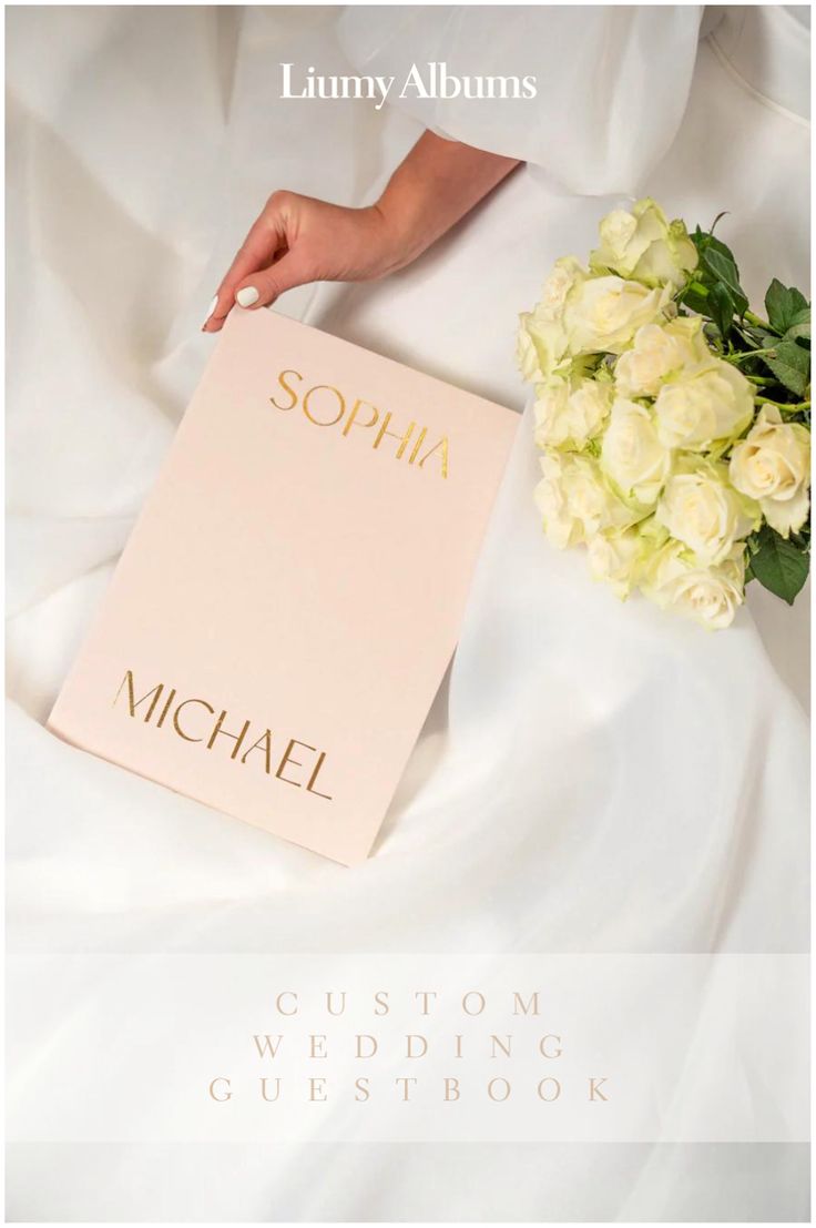 the wedding album is being held by a bride's hand on her white dress