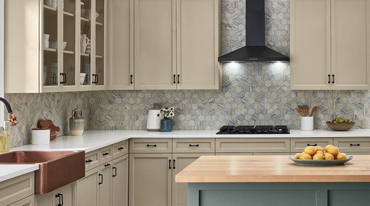 a kitchen with wooden counter tops and white cupboards, an island in the middle