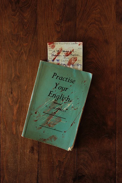 an old book with writing on it sitting on top of a wooden floor next to a pair of scissors