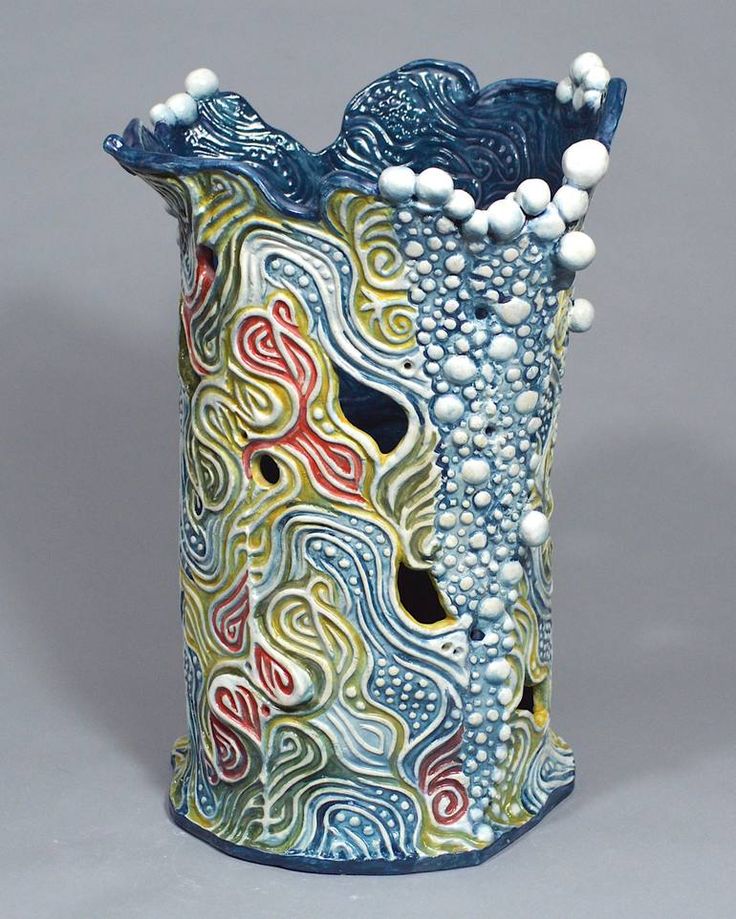 a blue vase with white balls on the top and an artistic design in the bottom