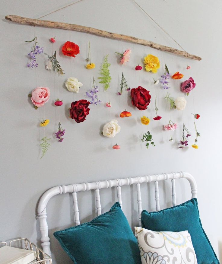 a white bed topped with lots of flowers next to a wall mounted on the side of it