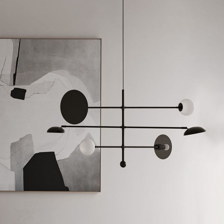 an abstract painting hangs on the wall next to a chandelier with five lights