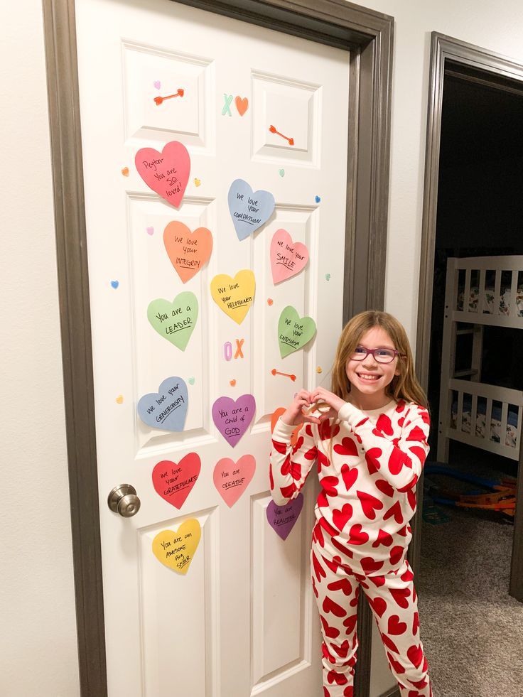 a girl in pajamas standing next to a door decorated with hearts