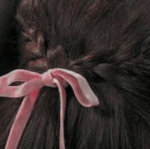 a close up of a woman's hair with a pink ribbon