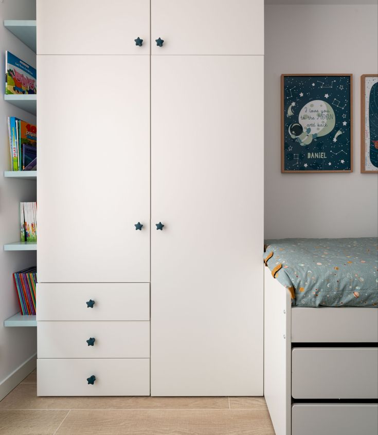 a bedroom with white cupboards and bookshelves next to a small child's bed