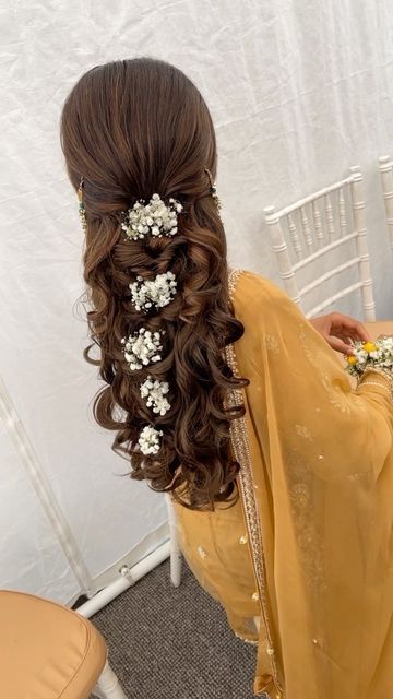 a woman with long hair and flowers in her hair is wearing a yellow sari