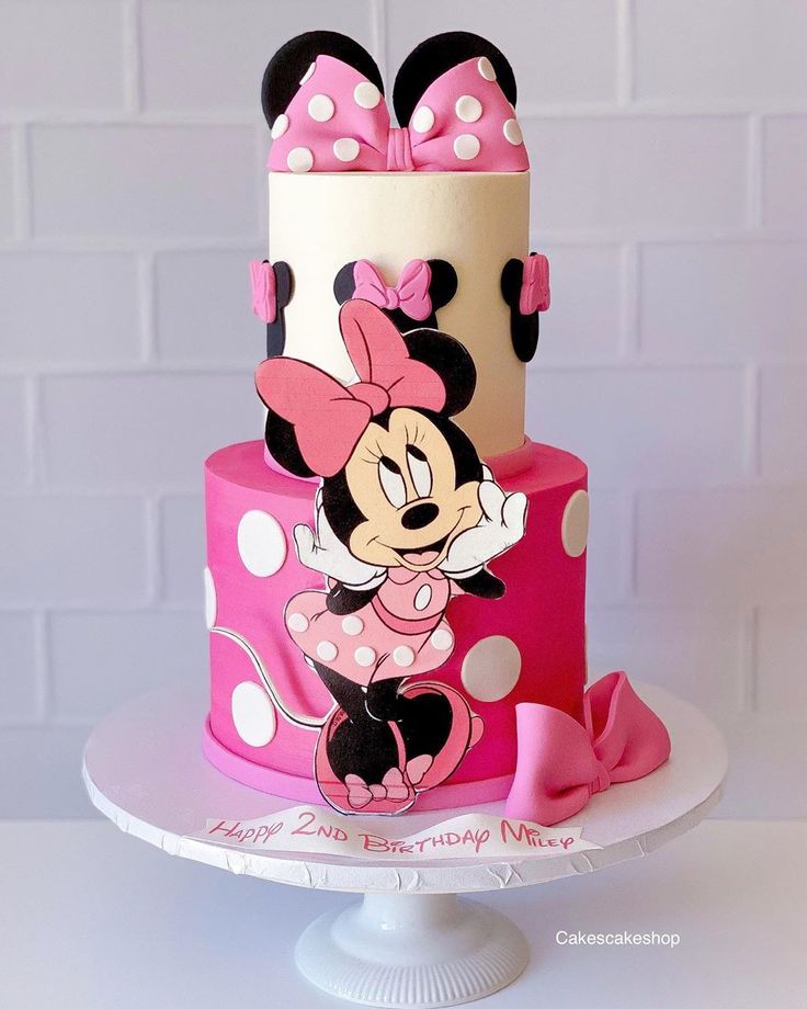 a pink and white cake with minnie mouse on top