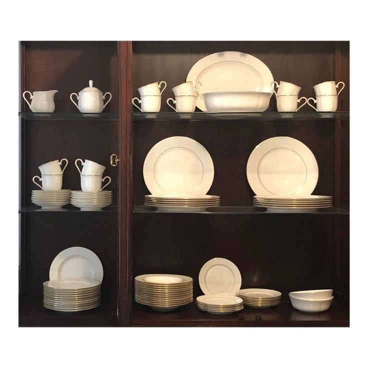 the shelves are filled with white dishes and china plates, cups and saucers on them