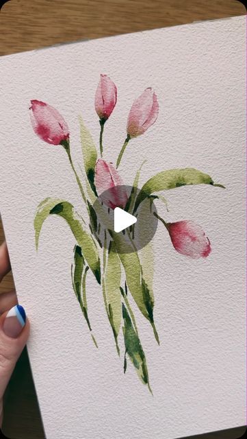 a person holding up a card with watercolor flowers on it