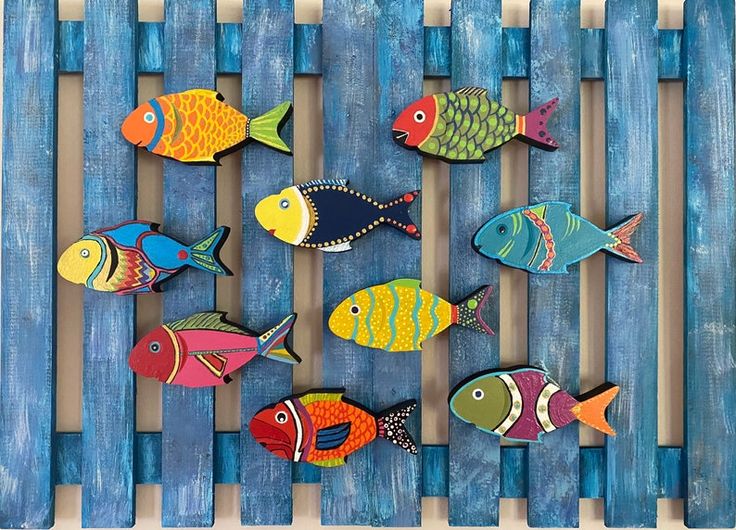 a group of colorful fish sitting on top of a blue wooden slatted fence