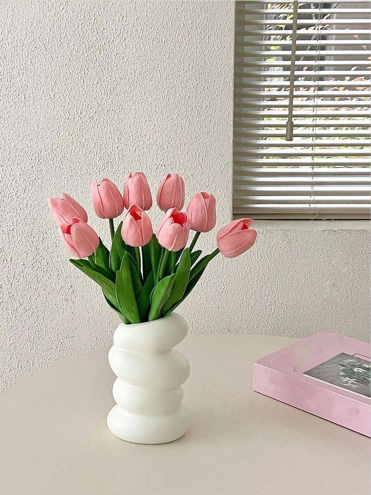 pink tulips in a white vase on a table