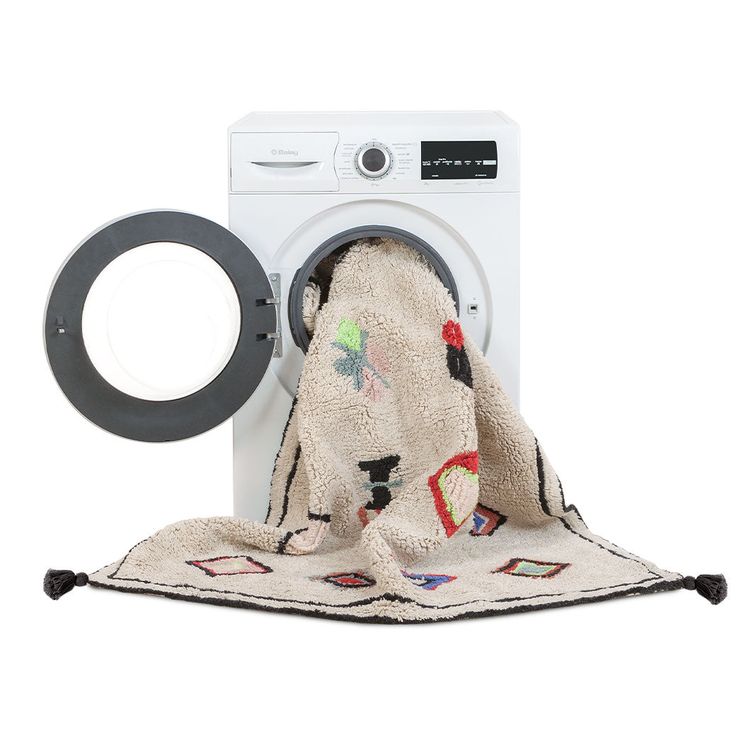 a white washer sitting next to a pile of towels on top of a rug