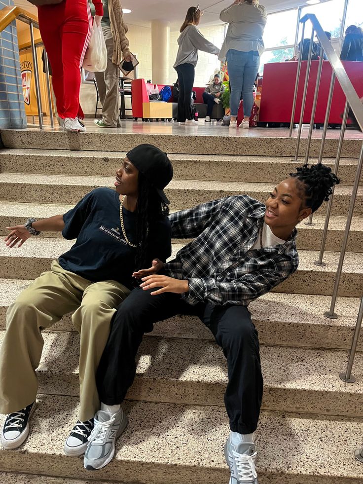 two young people sitting on the steps in an airport