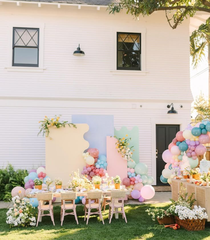 an outdoor party setup with balloons, tables and chairs in front of a white house