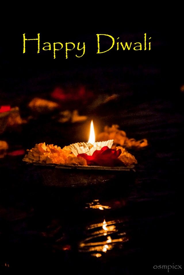 happy diwali greeting card with lit candle in dark water and lights reflecting on the surface