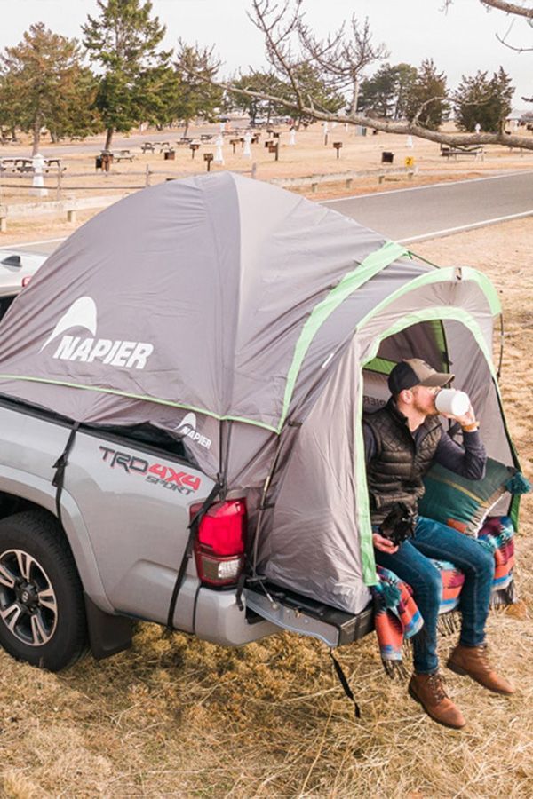 a man sitting in the back of a truck with a tent on it's bed