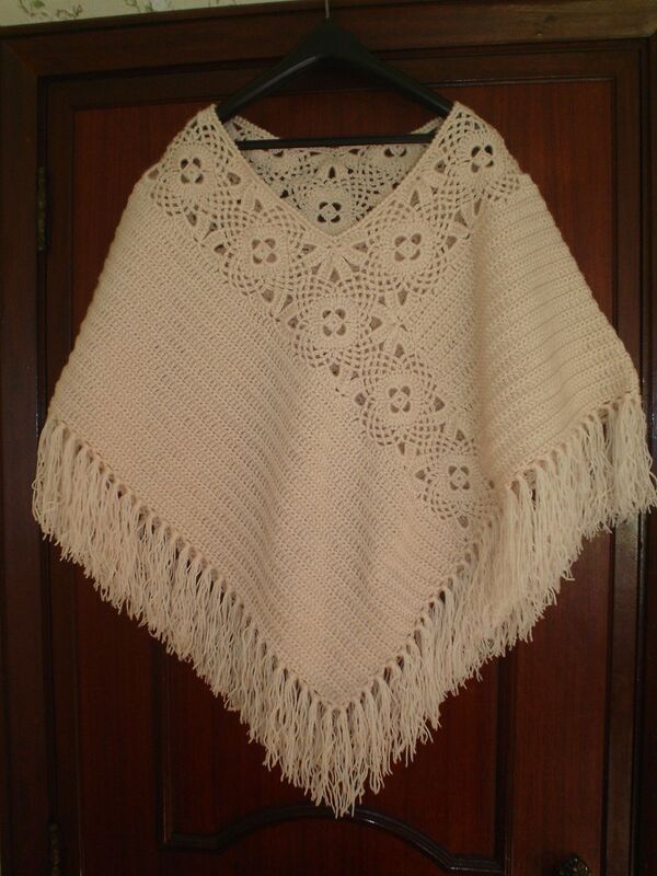 a white crocheted shawl hanging on a wooden hanger in front of a door