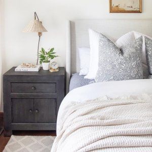 a bed with white sheets and pillows next to a night stand