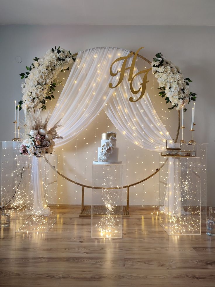 a wedding cake on a table surrounded by candles and flowers in front of a backdrop with lights