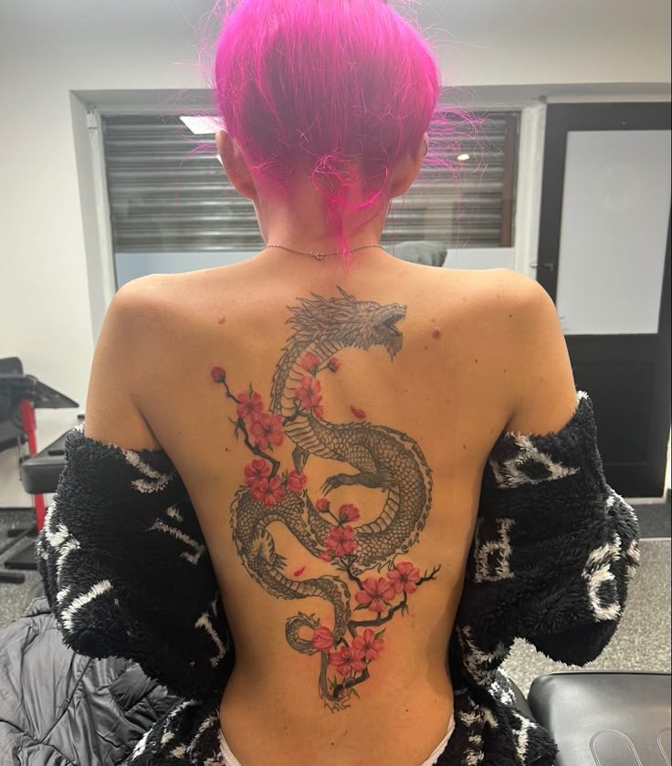 a woman with pink hair and tattoos on her back