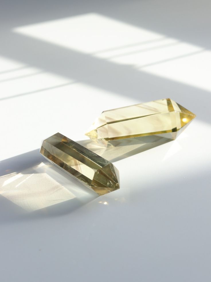 two yellow diamonds sitting next to each other on a white surface with sunlight coming through the window